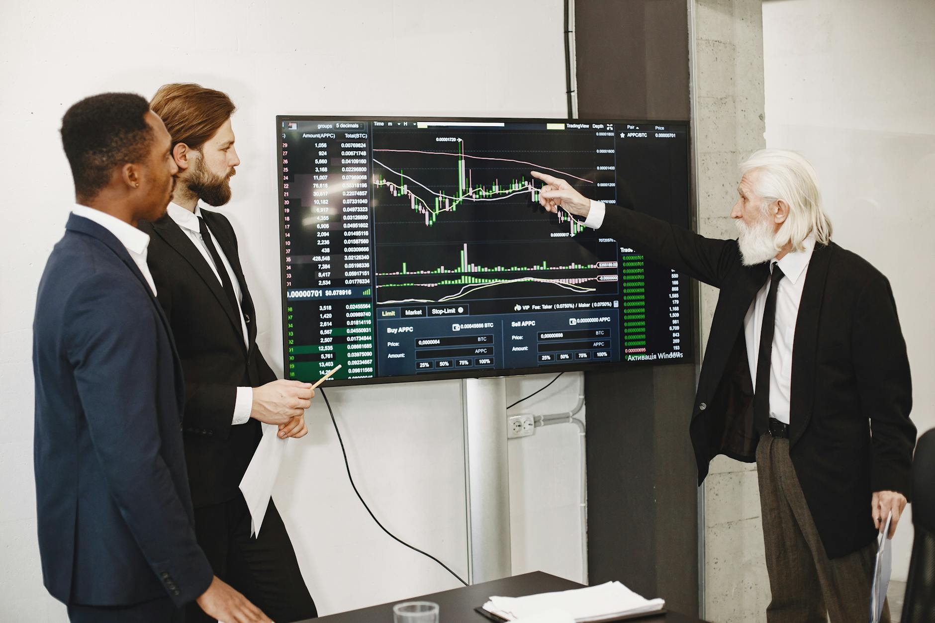 A Diverse Business Team In A Meeting Analyzing Stock Market Data On A Screen.