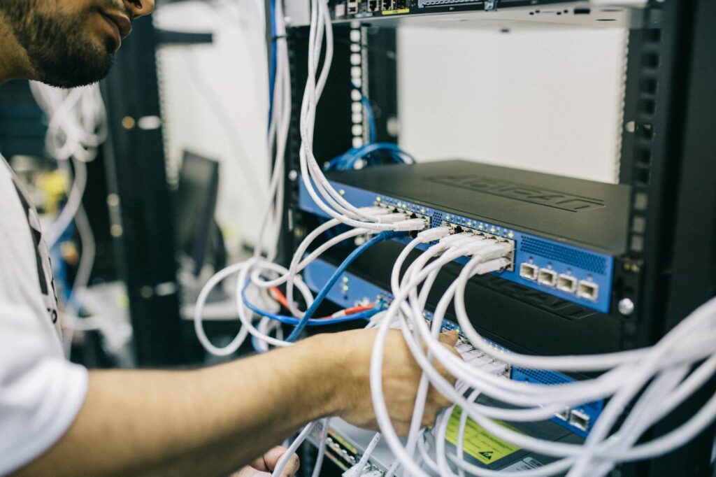 An It Professional Configuring Network Cables In A Server Rack, Focusing On Ethernet Connections.