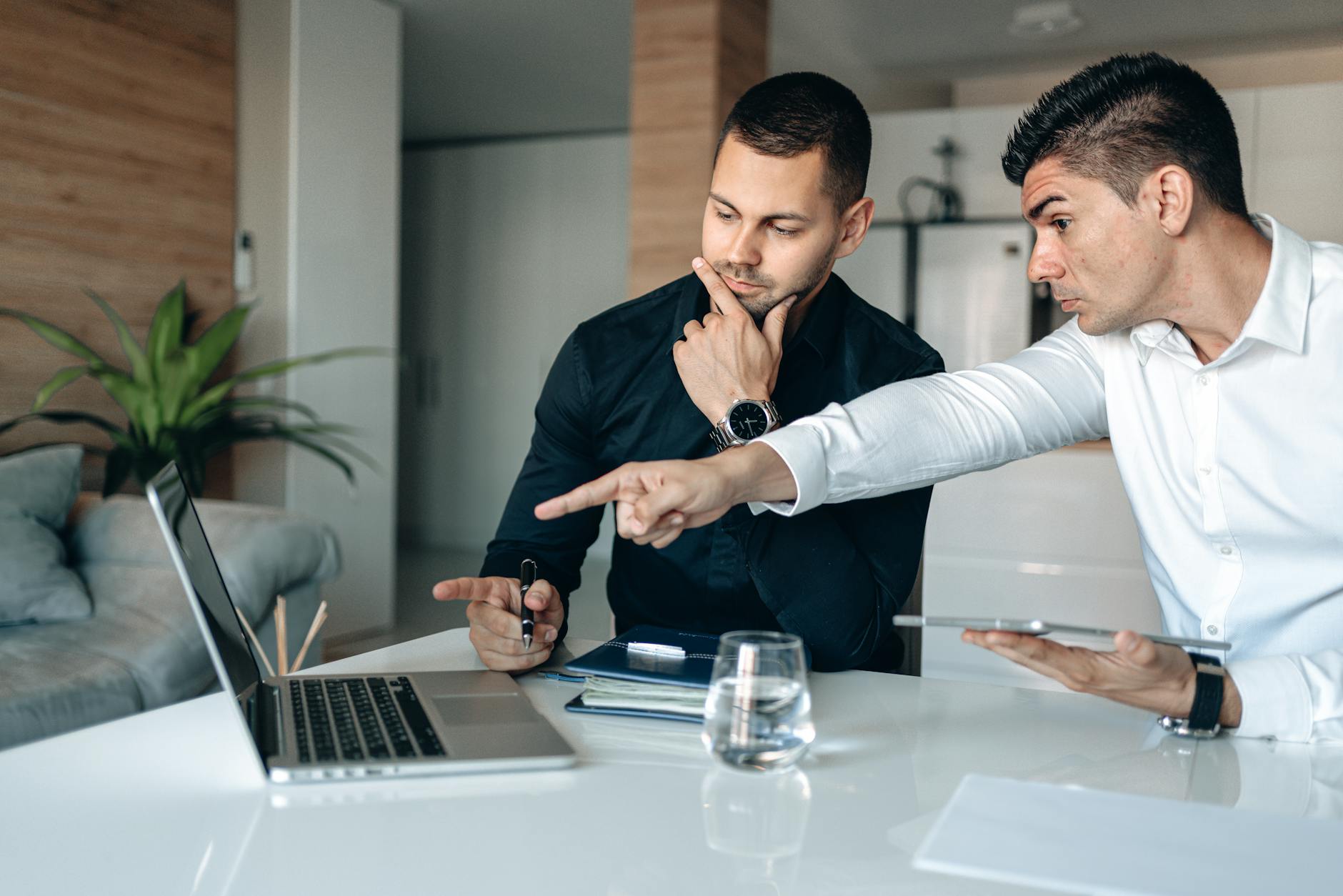 Two Men In An Office Intensely Focusing On A Lapto