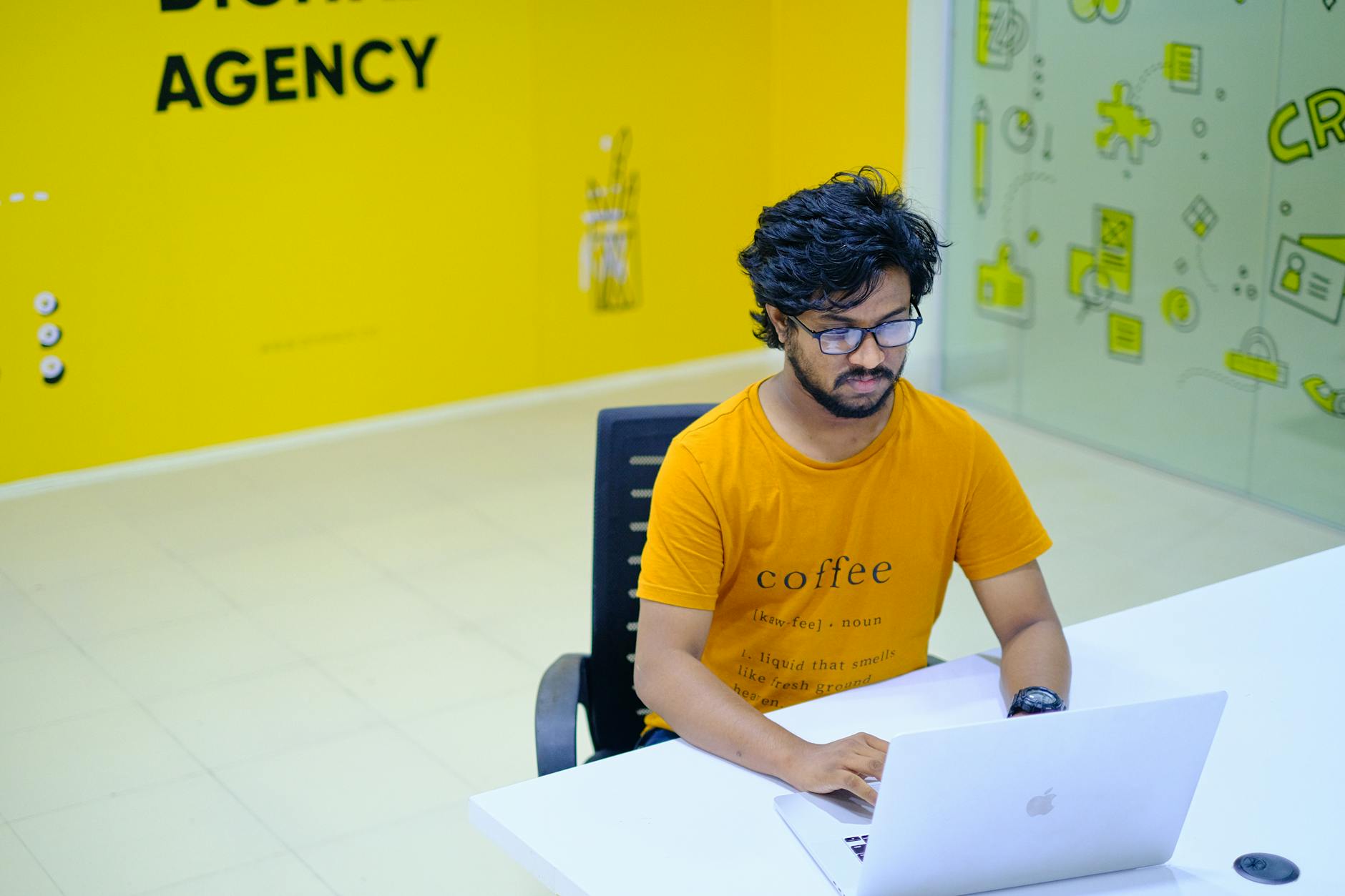 Young Man Wearing Eyeglasses Working On Laptop In