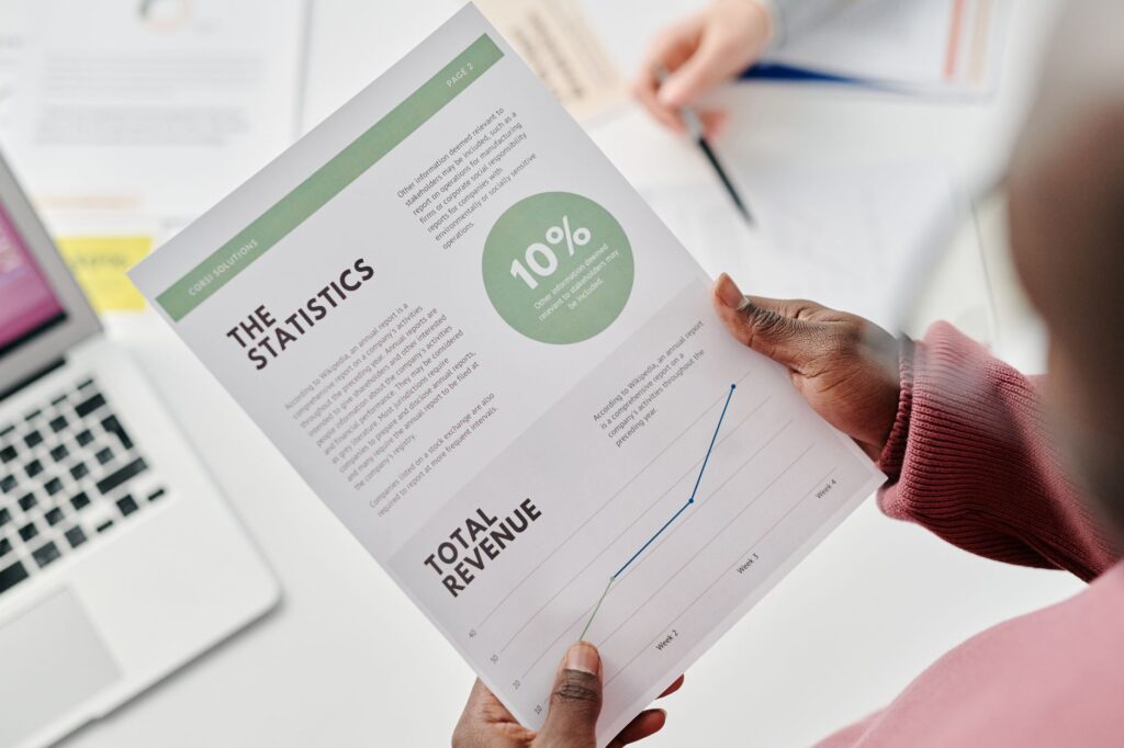 Revenue Growth Consulting: Expert Strategies For Business Success 2 Hands Holding A Statistical Report During A Business Meeting. Includes Revenue Graphs And Analysis.