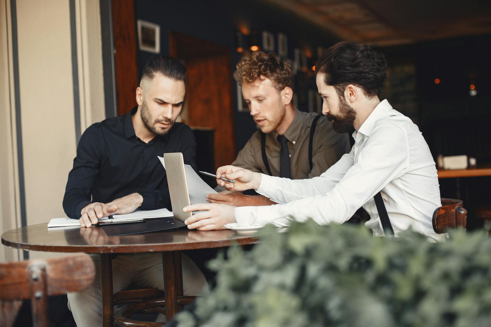 Three Young Men Collaborating In A Cozy Cafe Setti 2