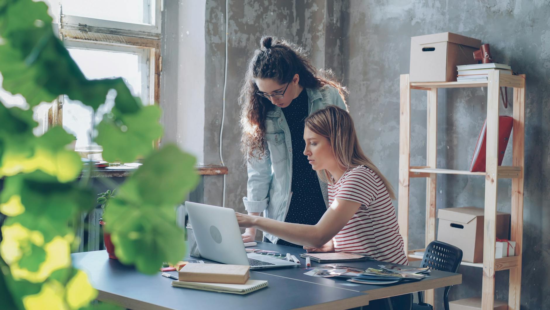 Two Young Women Working Together In A Modern Offic