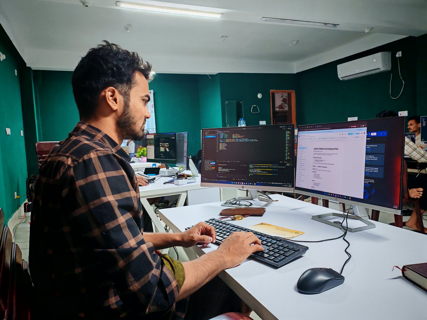 A Software Developer Working On Code At A Dual Mon