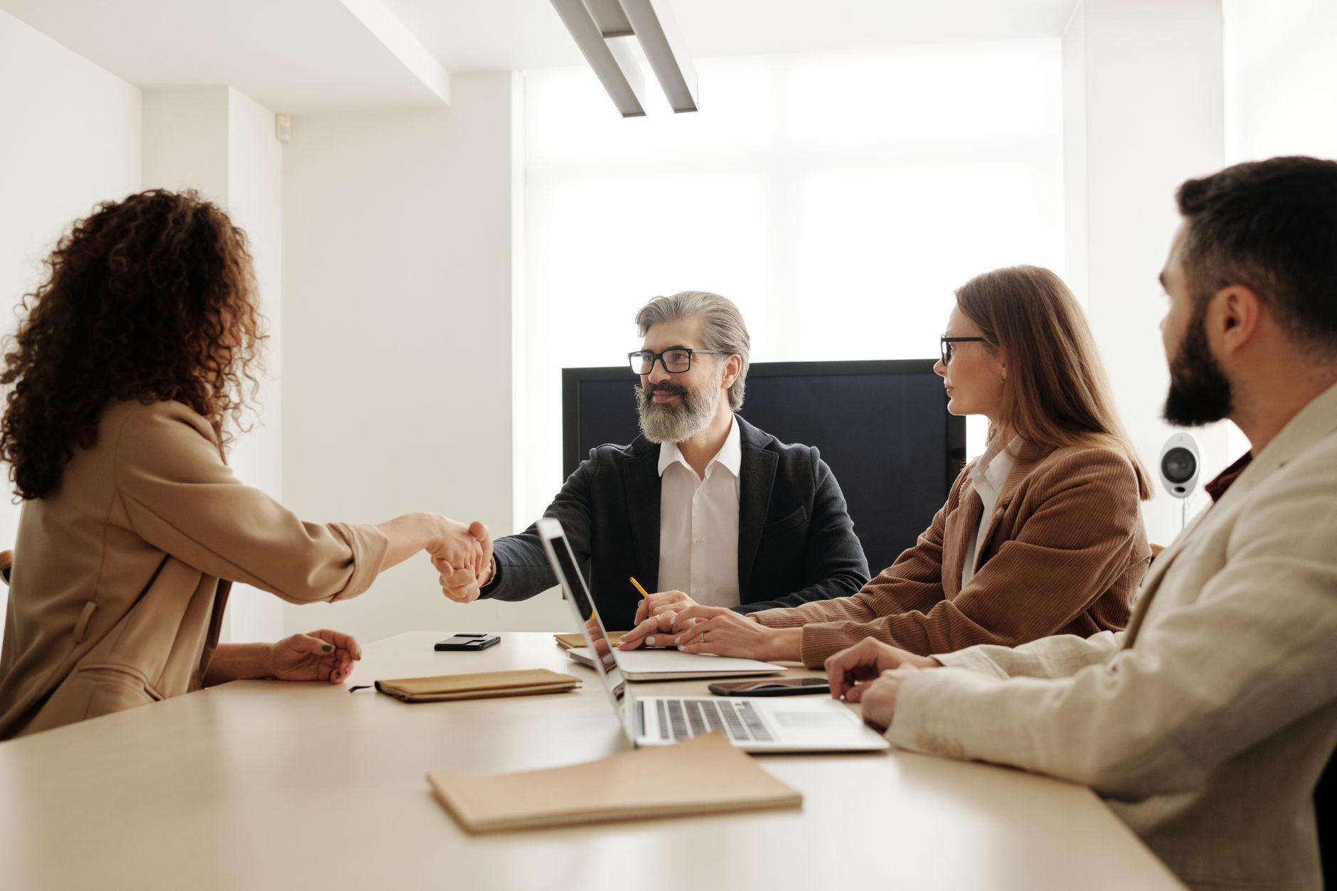 Colleagues In An Office Celebrating A Successful Negotiation With A Handshake.